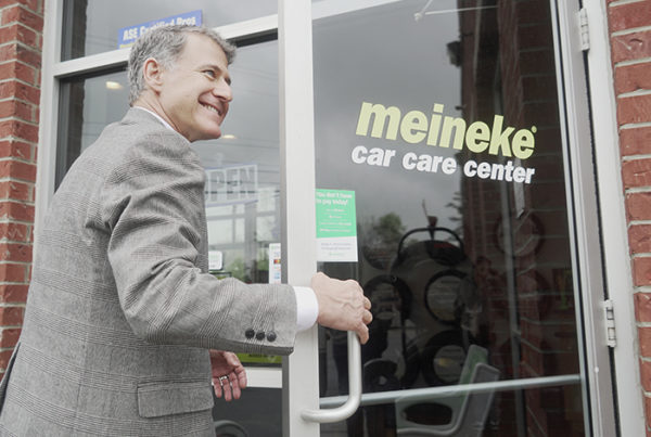 Smiling man entering Meineke car care center