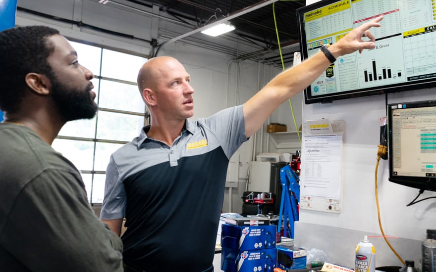 Meineke employee looking over data with customer